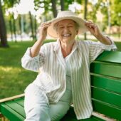 Granny In Hat Sitting On The Bench In Summer Park